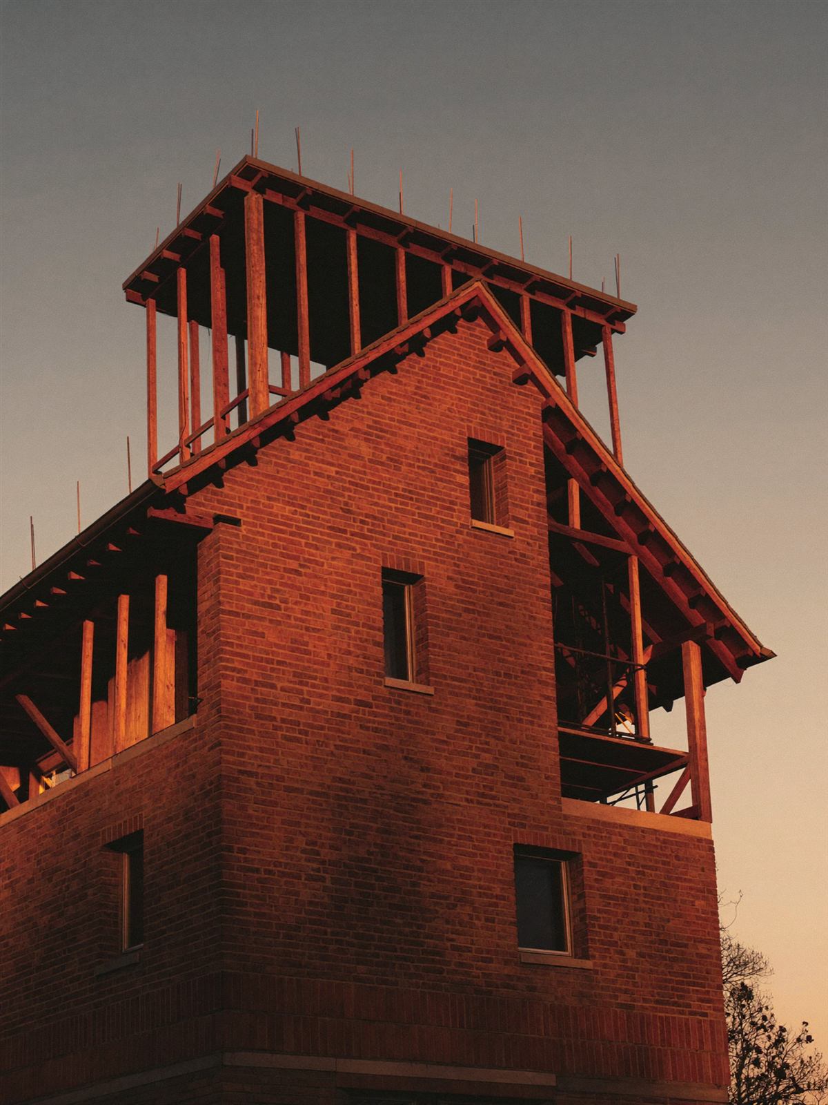 Brick gable and timber roof structure under construction at dusk
