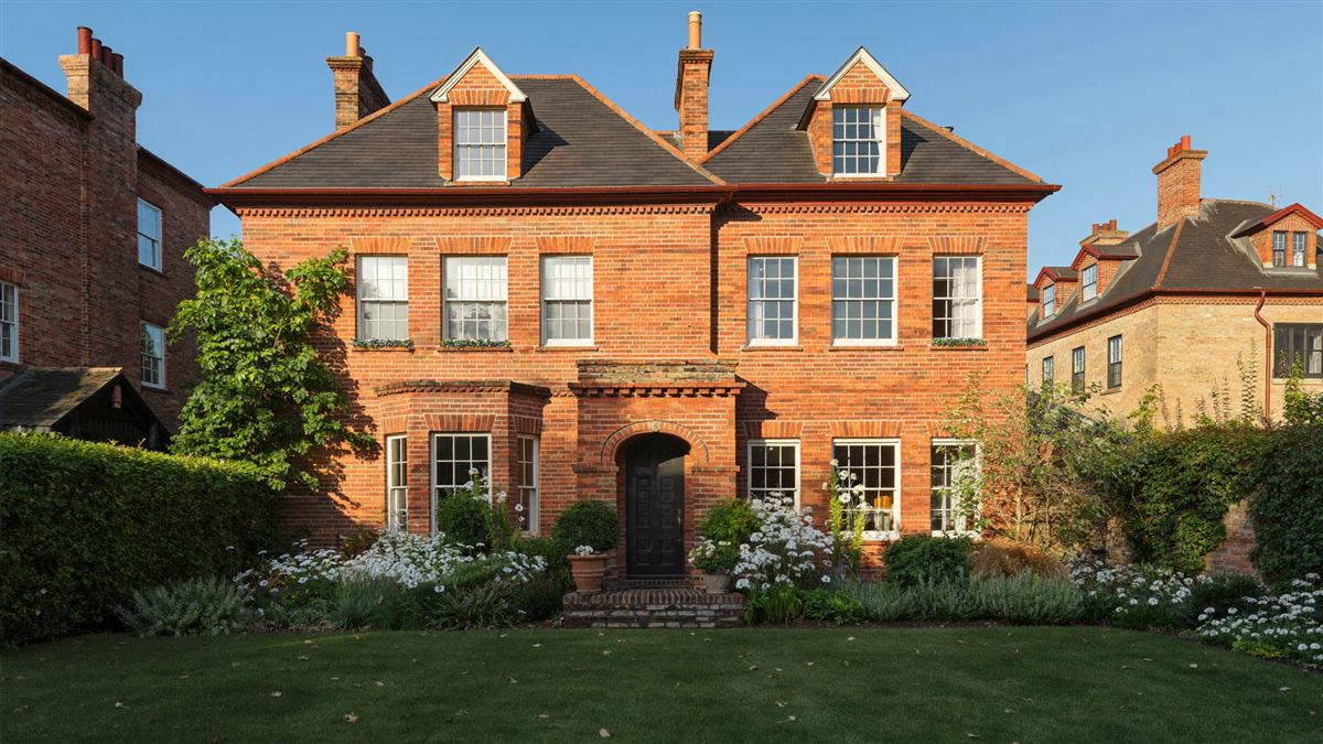 Red-brick terraced house with a fresh front garden in golden light